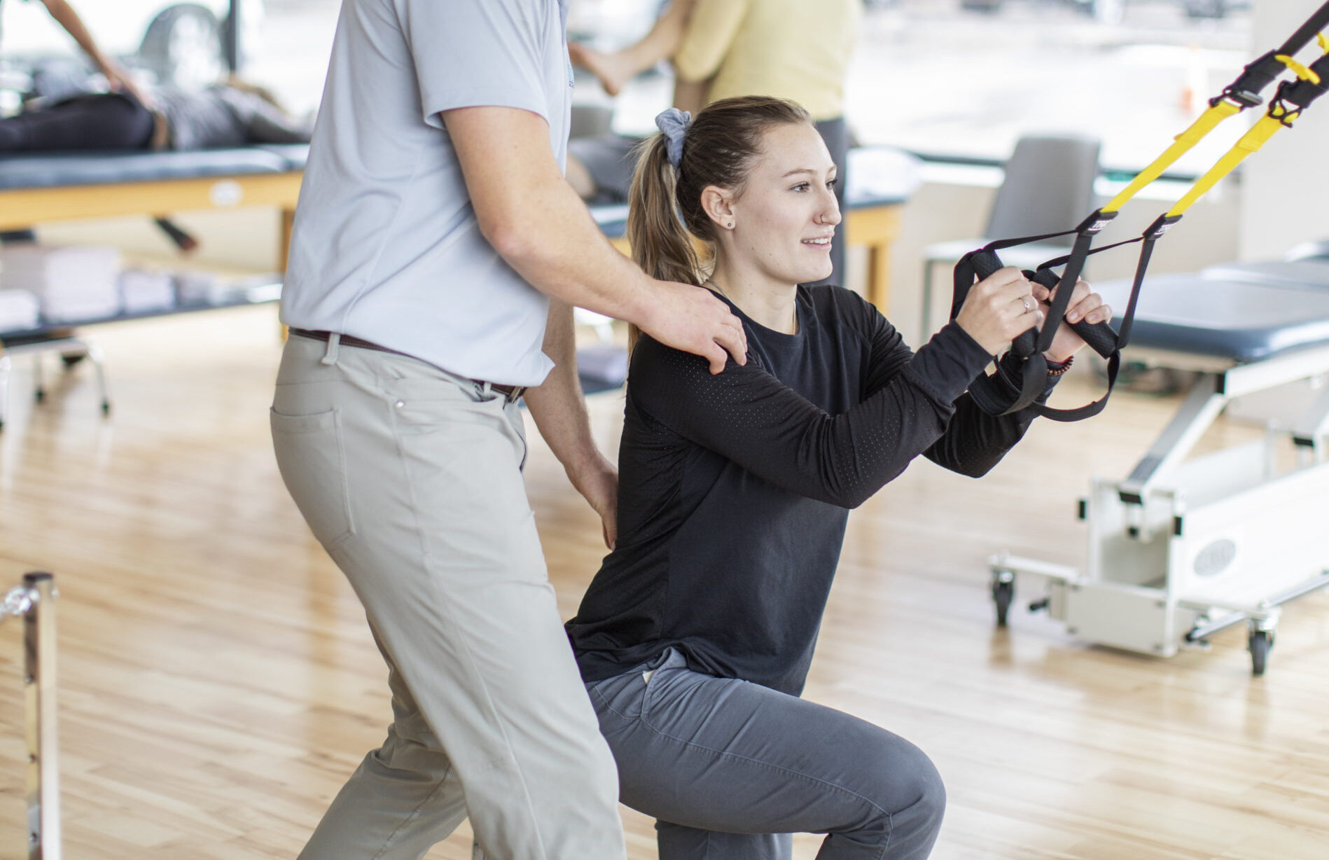 A physical therapist working with a patient on the TRX stretching equipment.